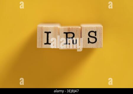 IRS-Akronym auf Holzblöcken, Draufsicht. Das Wort IRS steht auf Holzwürfeln vor einem hellgelben Hintergrund. Konzept für US-Steuern, interne Revenu Stockfoto