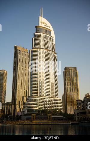 Ein vertikales Niedrigwinkelfoto moderner Wolkenkratzer in der Innenstadt von Dubai während der goldenen Stunde. Das zentrale Gebäude hat eine geschwungene weiße Spitze und n Stockfoto