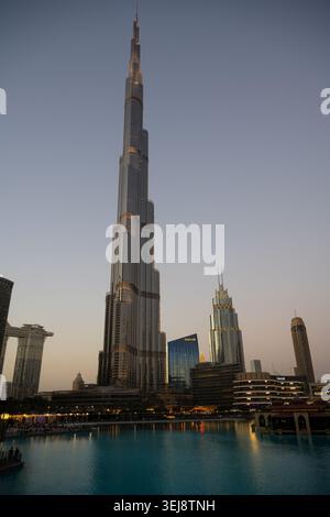 Ein vertikales Weitwinkelfoto des Burj Khalifa, des höchsten Gebäudes der Welt, das in der Abenddämmerung über der Skyline von Dubai thront. Die Szene-Featur Stockfoto