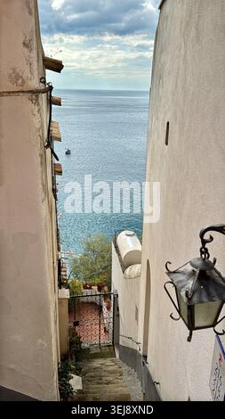 Malerischer Blick durch eine enge Straße in Positano, Italien, mit traditionellen Gebäuden, Vintage-Laterne und einem Blick auf den Strand und das türkisfarbene Meer Stockfoto