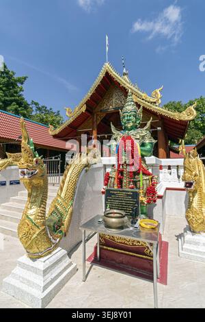 Dok Kham Tai, Phayao, Thailand - 28. Mai 2026: Wat Chaloem Phra Kiat (Wat San Pa Fang), Schutzfigur mit Opfertisch und Nagagelgeländer. Stockfoto