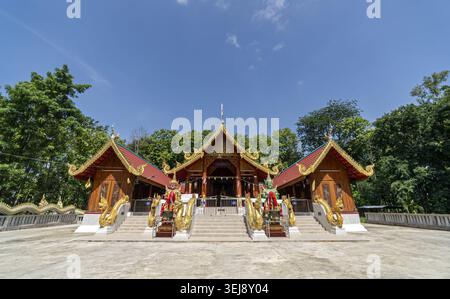 Dok Kham Tai, Phayao, Thailand - 28. Mai 2026: Wat Chaloem Phra Kiat (Wat San Pa Fang), Holzsaal mit Naga und Schutzfiguren. Stockfoto