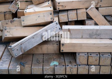 Der Stapel schwerer Holzbalken mit schwarzen Befestigungselementen liegt auf einer Holzlattenfläche. Stockfoto
