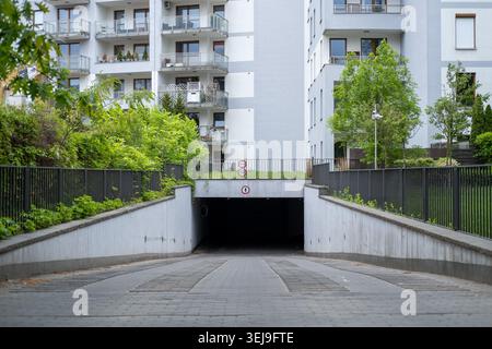 Rampe, die in eine Tiefgarage in einem modernen Apartmentgebäude absteigt. Stockfoto