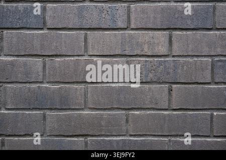 Nahaufnahme einer Wand aus dunkelgrauen rechteckigen Ziegeln. Stockfoto