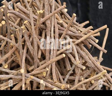 Haufen Lakritwurzeln auf schwarzem Stoffhintergrund. Stockfoto