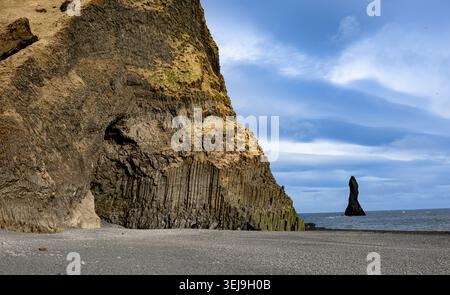 Basaltklippe und schwarzer Sandstrand mit vulkanischem Meer an der dramatischen isländischen Küste Stockfoto