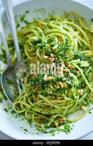 Ein lebhaftes Nahaufnahme-Foto mit Spaghetti, die großzügig mit frischem Knoblauch-Pesto überzogen sind. Das hellgrüne Pesto klammert sich an die Nudeln, cre Stockfoto