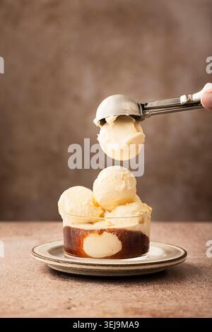Vertikal Shot oder affogato al Caffe, typisch italienisches Dessert, häufig als Ende des Essens, jemand hält einen Eislöffel in der Hand Stockfoto