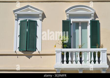Italienisches Gebäude mit zwei Fenstern mit grünen Fensterläden und einem Balkon mit einem Zitronenbaum in Vasto, Italien Stockfoto