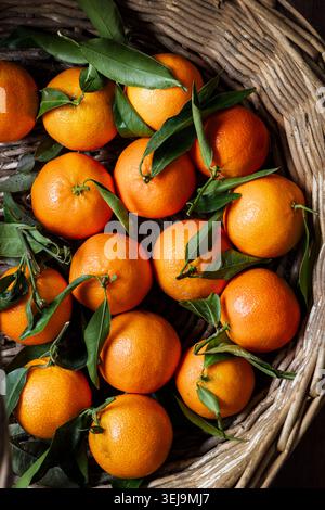 Ein rustikaler Korb gefüllt mit frischen Clementinen. Stockfoto
