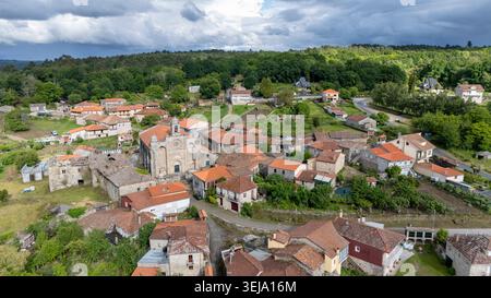 Blick aus der Vogelperspektive, die die bezaubernde Architektur und das historische Flair des Dorfes, umgeben von üppigen grünen Hügeln, einfangen Stockfoto
