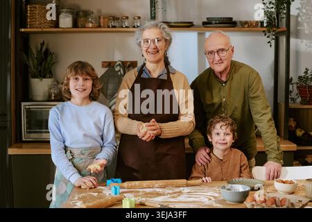 Porträt eines Seniorenpaares mit Kindern, die gemeinsam zu Hause backen Stockfoto