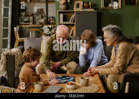 Seniorenpaar mit Kindern, die zu Hause Brettspiele spielen Stockfoto