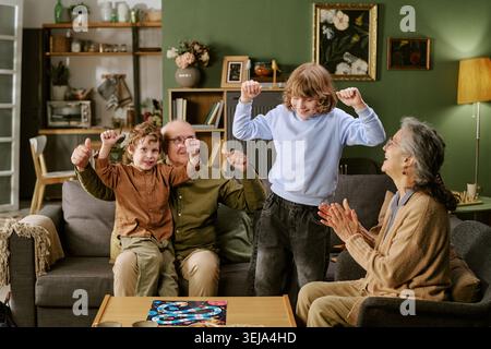Seniorenpaar mit Kindern, die zu Hause eine Spieleabende feiern Stockfoto