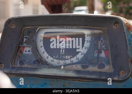 Eine überkopfnahe Ansicht zeigt ein großes graues Dreispeichen-Lenkrad, das über einem rustikalen blauen Traktortachometer platziert ist. Stockfoto