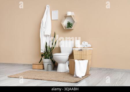 Das Innere des Toiletten mit Toilettenschüssel, Korb und Bademantel Stockfoto