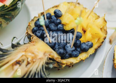 Frische Ananas zur Hälfte gefüllt mit Heidelbeeren und in Würfel geschnittenen Früchten Stockfoto