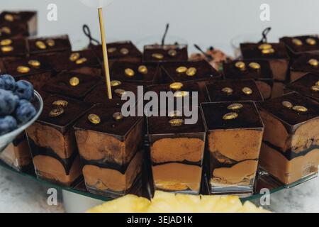 Schokoladenwürfel mit Goldgarnitur, ordentlich auf Glas angeordnet Stockfoto