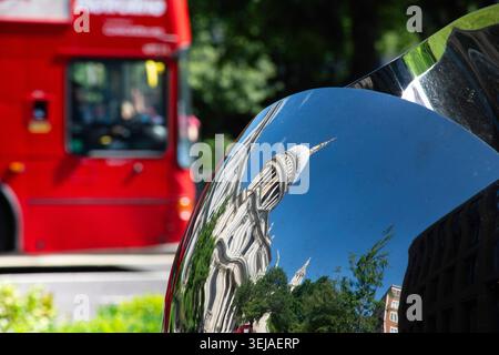 Reflexion der St. Paul’s Cathedral auf einer polierten Oberfläche, hinter der ein Teil eines berühmten roten Londoner Busses vorbeifährt Stockfoto