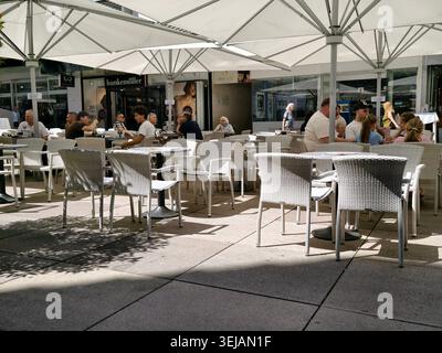 PFORZHEIM, DEUTSCHLAND - 28. MAI 2026 Gäste genießen Entspannung und Freizeit in einem gemütlichen Straßencafé mit weißen Sonnenschirmen und Tischen auf einer sonnigen Terrasse Stockfoto