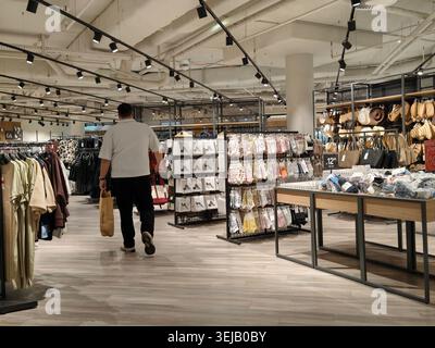 HPFORZHEIM, DEUTSCHLAND - 28. MAI 2026 Ein männlicher Kunde mit einer Papiertüte geht durch ein großes Bekleidungsgeschäft mit Kleiderständern und Accessoires Stockfoto