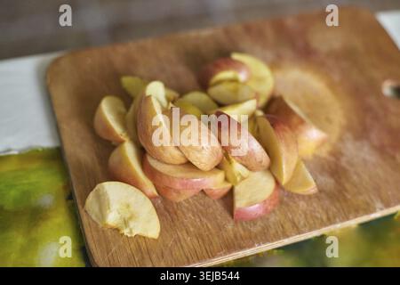 Nahaufnahme von frisch geschnittenen roten Äpfeln auf hölzernem Schneidebrett für gesunde Snackzubereitung Stockfoto