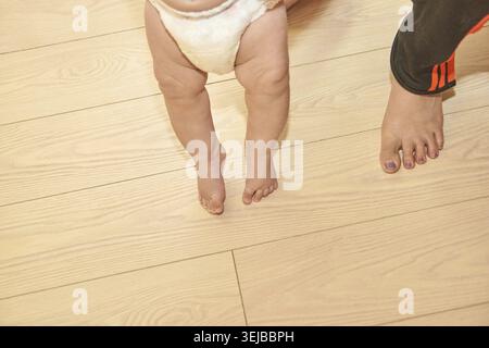 Babystufen Kaukasische Füße Für Kleinkinder Und Erwachsene Auf Holzboden Mit Windel Stockfoto