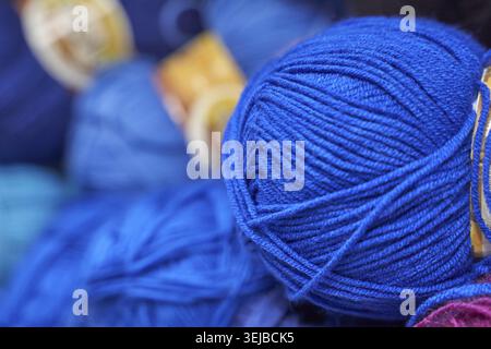 Nahaufnahme leuchtend blauer Garnbällchen im Strickkorb mit farbenfrohem Hintergrund zum Basteln Stockfoto