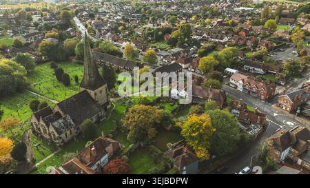 Eine erhöhte Perspektive zeigt eine charmante ländliche Gemeinde mit traditioneller Architektur, üppigem Grün und einem prominenten Kirchturm Stockfoto