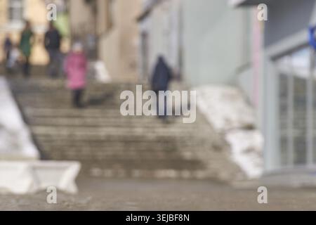Verschwommene urbane Straßenszene mit Menschen auf Stufen im winterlichen Stadtbild Stockfoto
