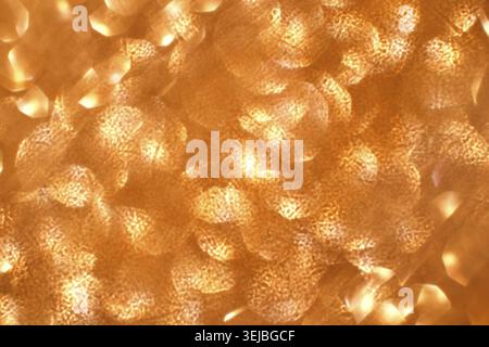 Abstraktes Muster aus orangen und goldenen Lichtreflexen für eine warme und schimmernde Textur Stockfoto