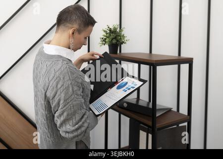 Frau, die Dokumente in einem Ordner in einem stilvollen Büro eincheckt Stockfoto
