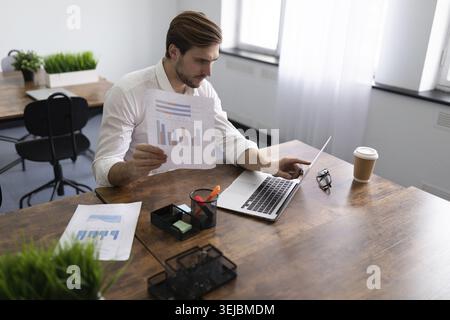 Geschäftsmann, der die finanziellen Angelegenheiten seines Unternehmens studiert und Diagramme in den Händen hält Stockfoto