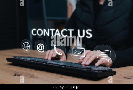 Kontaktieren Sie uns und das Kundendienstkonzept. Person, die auf der Tastatur mit Kommunikationssymbolen wie Telefon, E-Mail, Adresse, Nachricht und Website-Adresse eingibt Stockfoto
