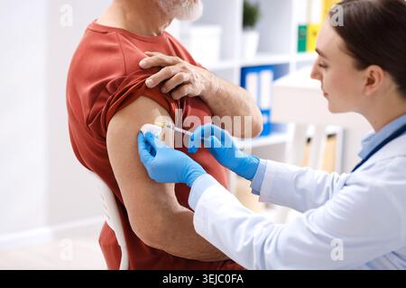 Krankenschwester in medizinischen Handschuhen impfend Mann im Krankenhaus, Nahaufnahme Stockfoto