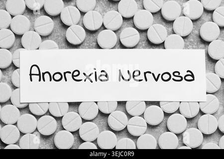Anorexie-Konzept. Karte mit Wörtern und Pillen auf grauem Hintergrund, Draufsicht Stockfoto