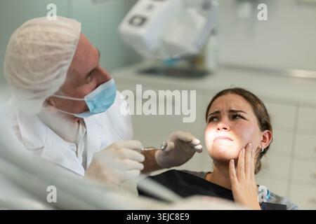 Reifer Mann Arzt Zahnarzt im weißen Mantel untersucht die Mundhöhle eines Mädchens in der Zahnheilkunde. Stockfoto