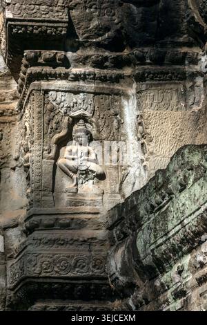 Nahaufnahme einer sitzenden Devata-Schutzgottheit, die in Relief in eine Sandsteinnische am Tempel Ta Prohm in Siem Reap, Kambodscha, gemeißelt ist Stockfoto