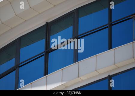 Gebäude mit geschwungenen Fenstern reflektiert den blauen Himmel Stockfoto