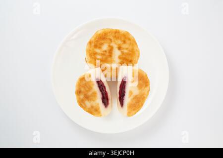 Traditionelle russische Syrniki Cottage Cheese Pancakes mit Beeren Marmelade Füllung isoliert auf weiß Stockfoto