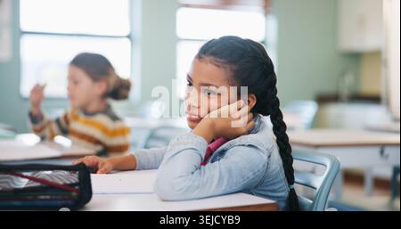 Gelangweiltes, erzieherisches und müdes Mädchen im Klassenzimmer für Test, Kinderentwicklung und Wissensmüdigkeit. Beurteilung, Burnout und Unterricht mit Schüler in der Schule Stockfoto