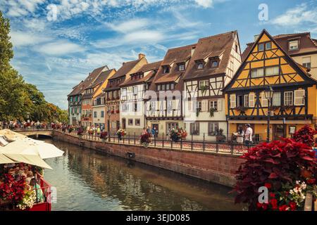 Colmar, Frankreich - 13.08.2023: Malerische Gebäude am Fluss mit traditionellen Holzfassaden und hellen Blumenkästen entlang eines malerischen Kanals Stockfoto
