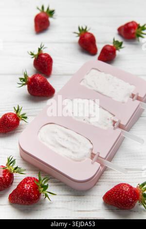 Zubereitung von Erdbeereis mit einer rosafarbenen Form, umgeben von frischen Erdbeeren Stockfoto