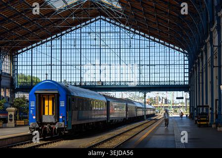 Ein Personenzug sitzt im historischen Terminalgebäude aus Glas und Eisen von Nyugati Pályaudvar in Budapest, Ungarn Stockfoto