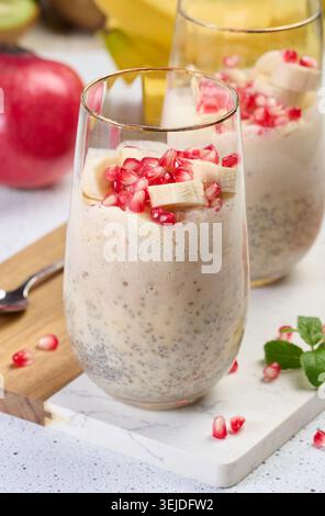 Ein Glas Chiasamen und Joghurt mit Bananenstückchen und Granatapfelkernen zum Nachtisch Stockfoto