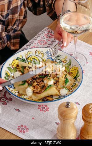 Person, die traditionelle Knödel mit einem Glas Wein isst Stockfoto