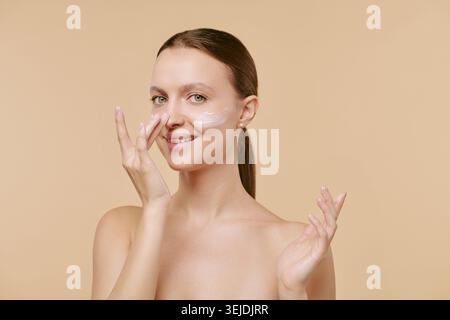 Porträt der erwachsenen Frau, die Gesichtscreme für Hautpflege-Branding aufträgt Stockfoto