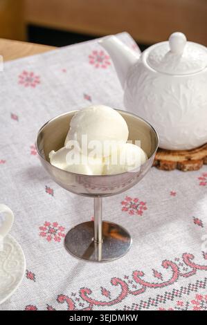 Kugeln mit weißem Eis auf einer gestickten Tischdecke Stockfoto