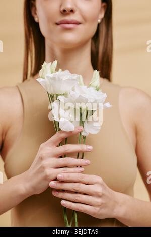 Erwachsene Frau hält Blumen für Beauty and Skincare Branding Stockfoto